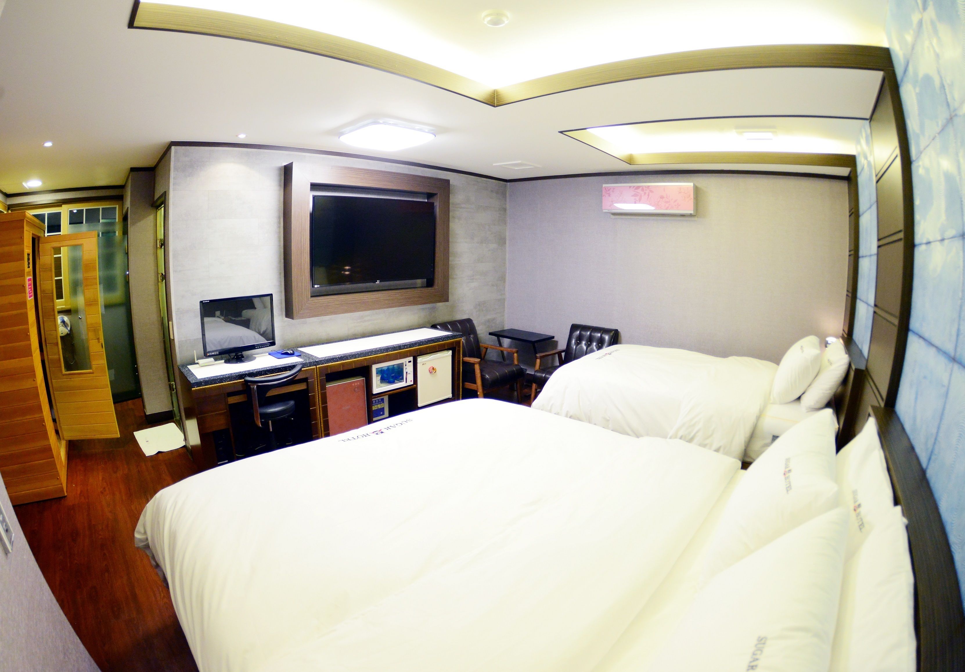 Una camera d'albergo con un letto grande, una scrivania con un computer e una TV fissata al muro.