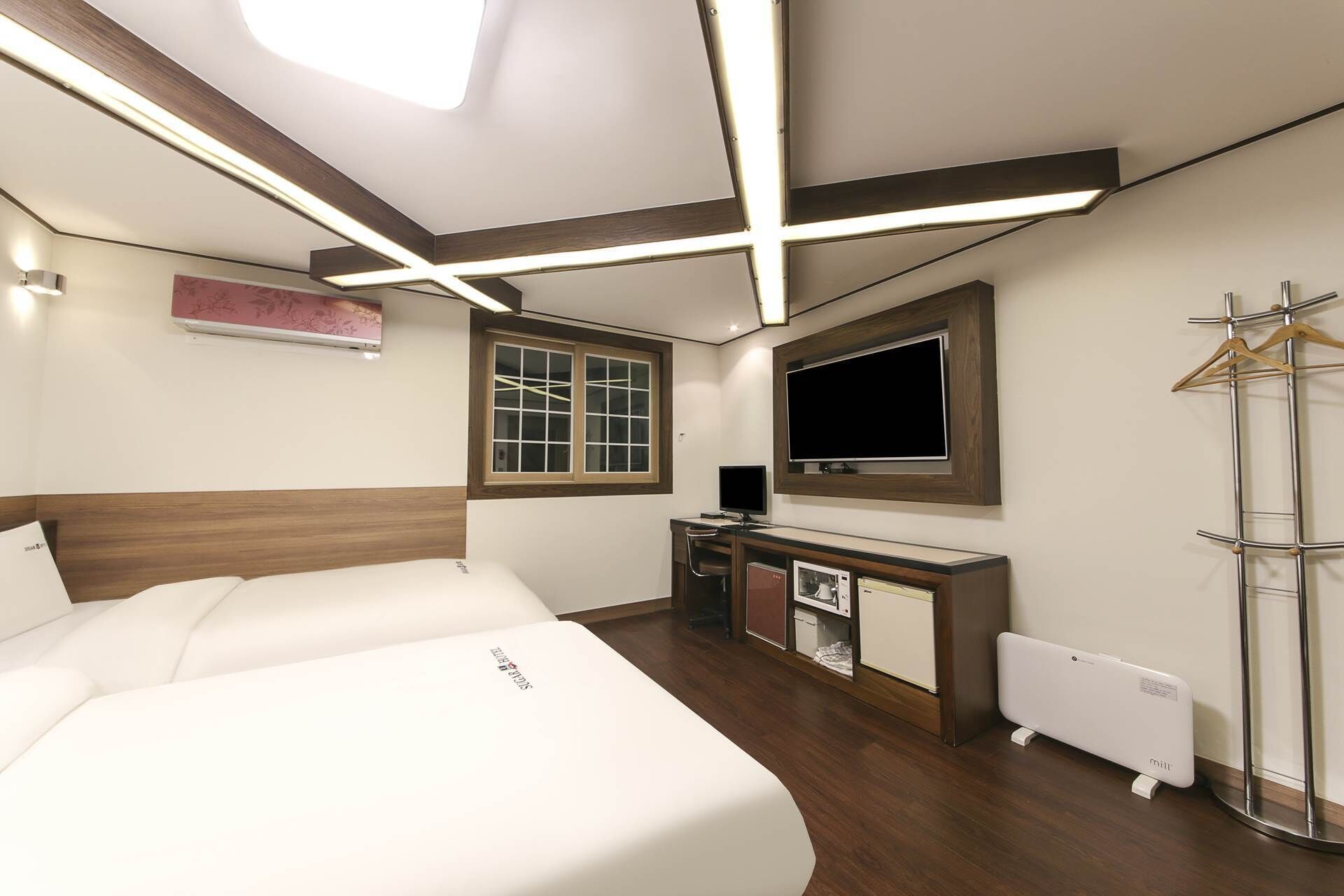 Una habitación de hotel con cama, escritorio, televisor y radiador.