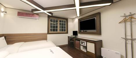 Una habitación de hotel con cama, escritorio, televisor y radiador.