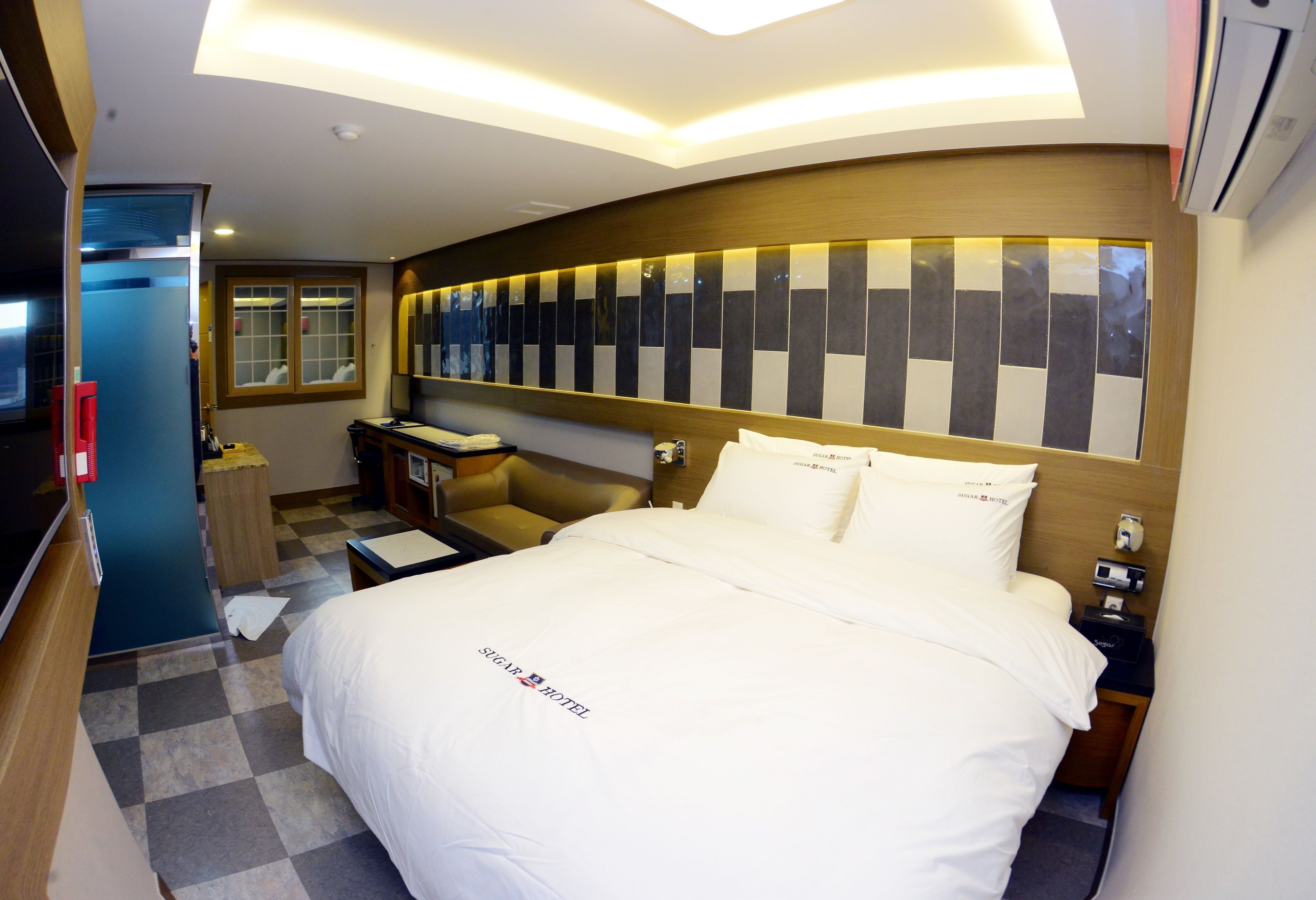 A hotel room with a large bed, a bedside table, a nightstand, a mirror, and a window.