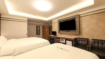 A hotel room with a large bed, a desk with a flat-screen TV, a seating area with a leather couch, and a minibar.