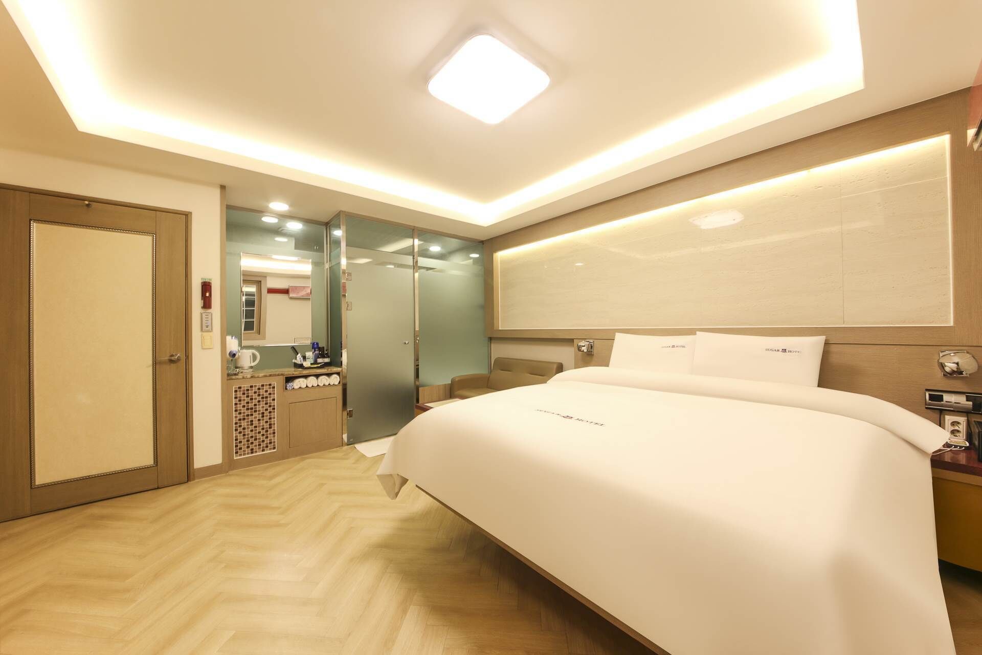 A hotel room with a large bed, a vanity with a mirror, and a small seating area.