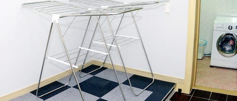 A laundry area with a metal drying rack and a washing machine.