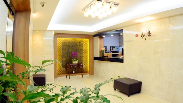 Un área de recepción moderna con mostrador, zona de estar y una pared decorativa con un diseño geométrico.
