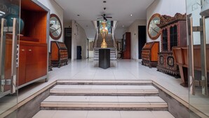 A spacious lobby with a grand staircase, wooden furniture, and a large clock on the wall. - Arimbi Pejaten Suites (Jakarta)