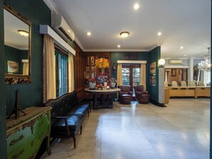 A spacious room with a large dining table, two leather chairs, a green cabinet, and a mirror. - Arimbi Pejaten Suites (Jakarta)