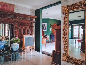 A lobby with ornate wooden furniture, a large mirror, and a green wall with a framed picture. - Arimbi Pejaten Suites (Jakarta)