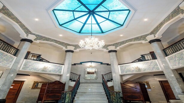 A grand lobby with a central staircase, high ceilings, and a skylight. - Arimbi Pejaten Suites (Jakarta)