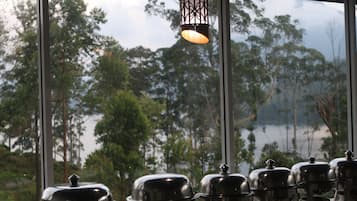 Vista a través de una ventana con reja de metal, una lámpara colgante y varios recipientes de comida cubiertos.
