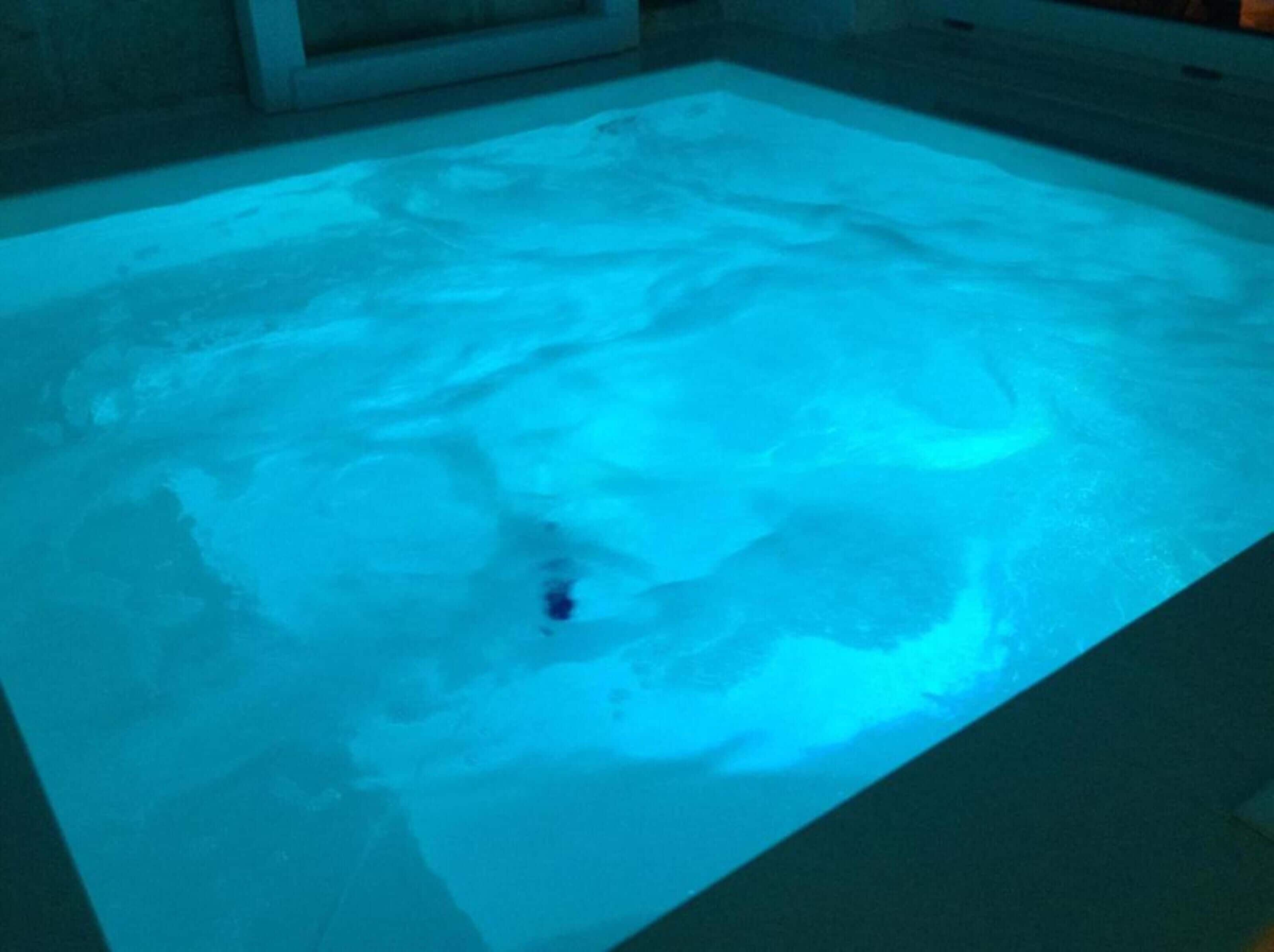 Una piscina rectangular con una luz azul.