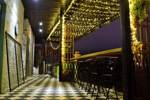 A checkered floor, a bar area with chairs, and string lights. - Rachana Hostel (Phnom Penh)