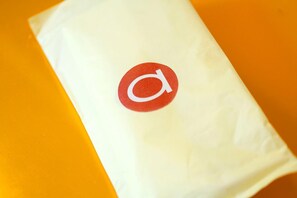 A white paper bag with a red logo on an orange surface. - Amaris Hotel Satrio Kuningan - Jakarta (Jakarta)