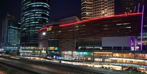A modern building with a prominent 'XXI' sign, large glass windows, and a red illuminated stripe. - Amaris Hotel Satrio Kuningan - Jakarta (Jakarta)