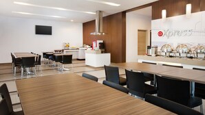 Un comedor moderno con una isla central, sillas negras y un mostrador tipo buffet con equipo para servicio de alimentos.