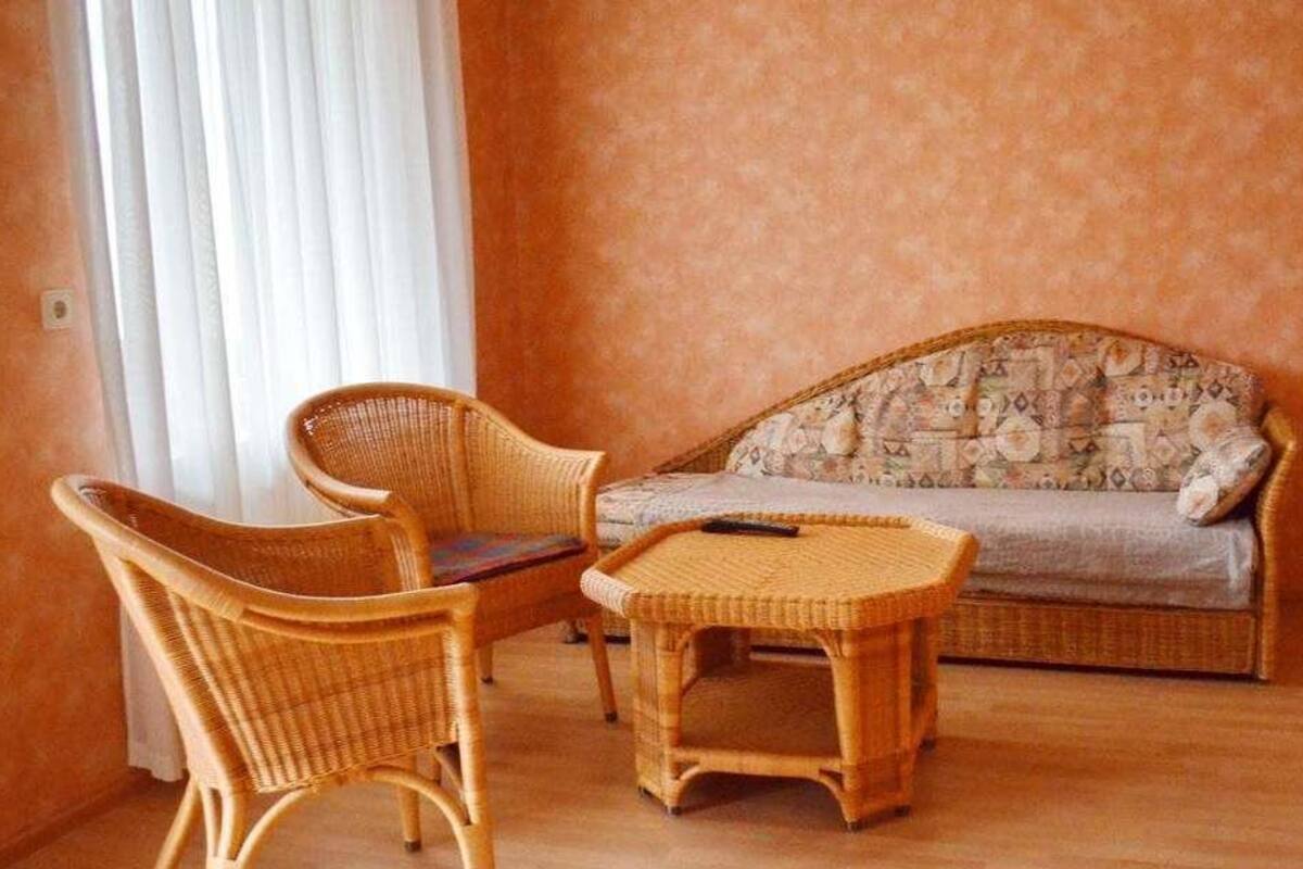 Una sala de estar con un sofá, dos sillones de mimbre, una mesita y un televisor.