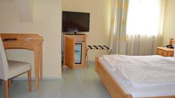 Quarto de hotel com uma cama, escrivaninha, televisão e minibar.