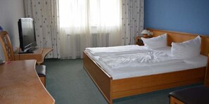 A hotel room with a wooden bed, a television on a wooden table, a small desk, and a window with curtains. - Hotel Alte Post (Laufenburg)