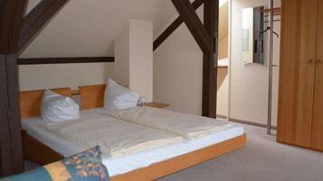 Une chambre avec un grand lit, des poutres en bois, une armoire et un miroir.