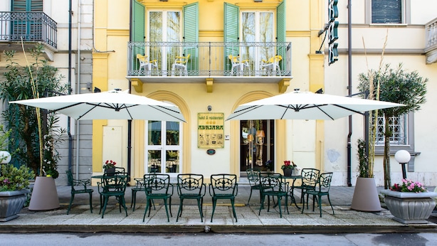 A hotel with outdoor seating, a balcony, and a sign indicating it's a restaurant. - Villa Adriana (Viareggio)