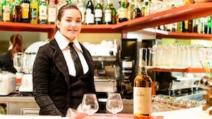 A bar area with a bartender, a bottle of Oban whisky, and empty glasses on a pink tray. - Villa Adriana (Viareggio)