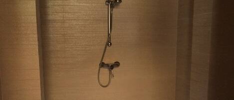 A bathroom with a shower, a toilet, and towels hanging on a rack.