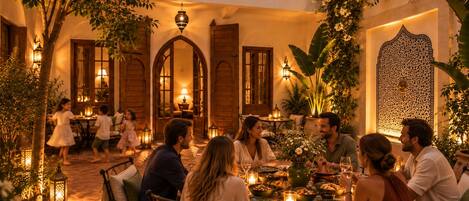 An outdoor dining area with a stone floor, wooden furniture, and warm lighting.