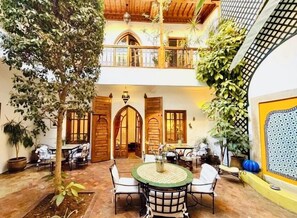 A courtyard with a round table, chairs, and potted plants. - Riad Scarlett (Marrakech)