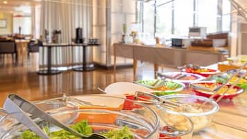 A buffet with various food items in clear bowls, including salads and dips.