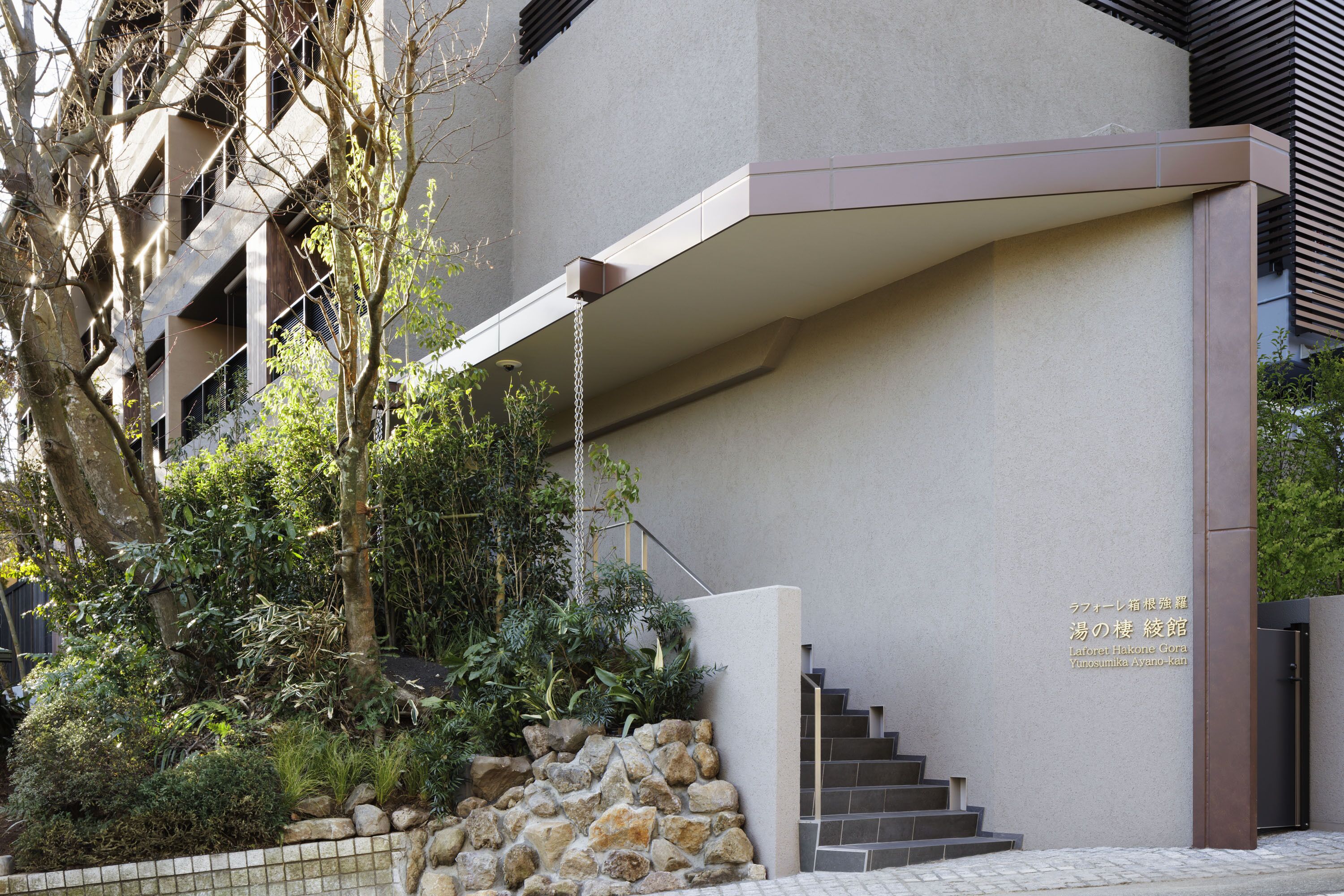 Un edificio moderno con una pared de piedra y escalones que conducen a una puerta.