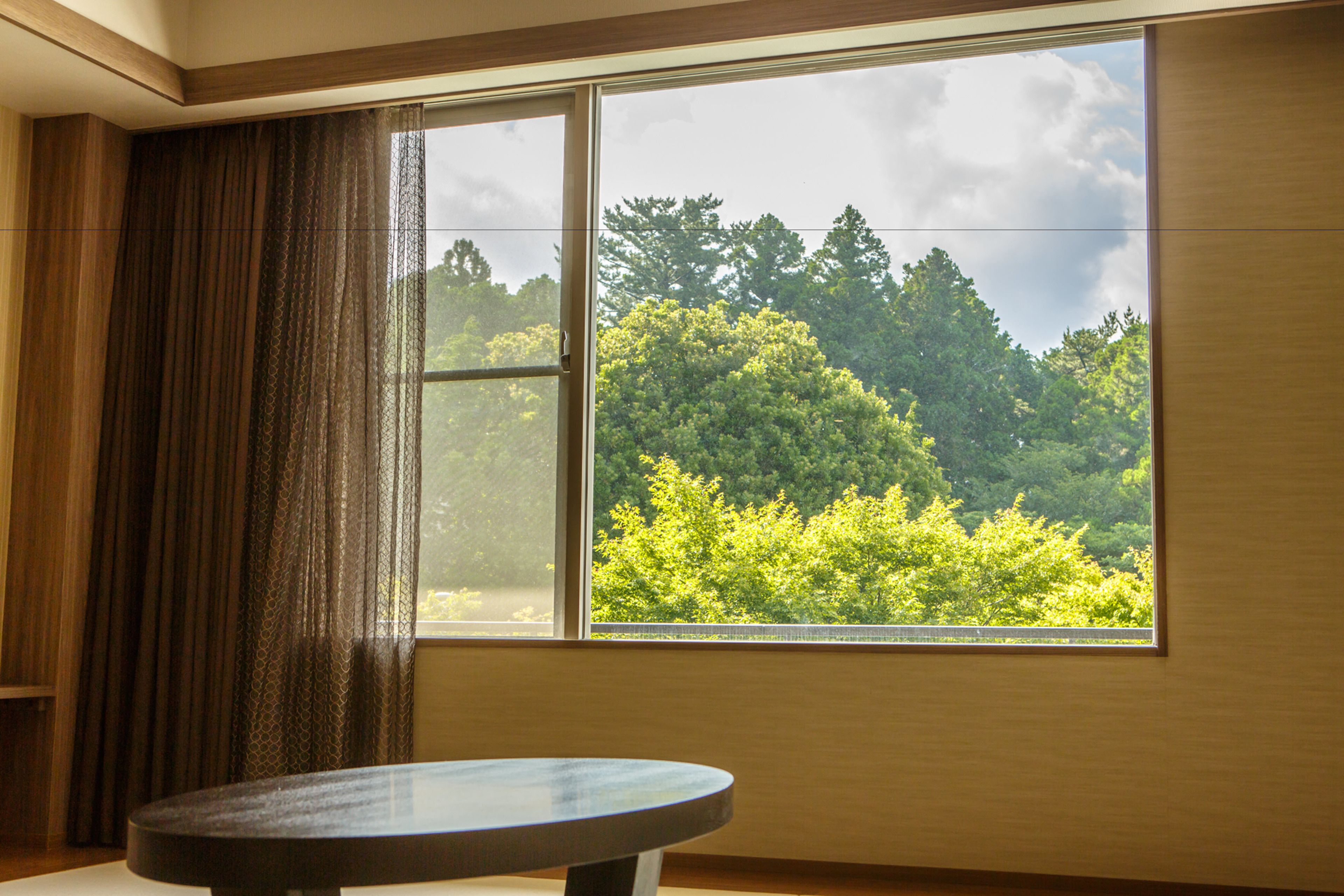 A room with a large window, a round table, and a curtain.