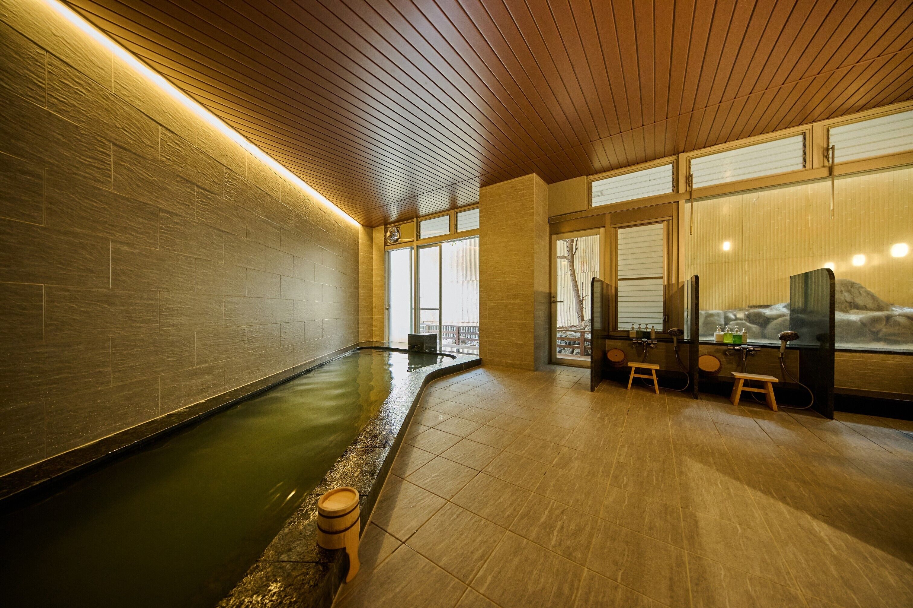 Un área de spa con jacuzzi, suelo de madera y amplios ventanales.