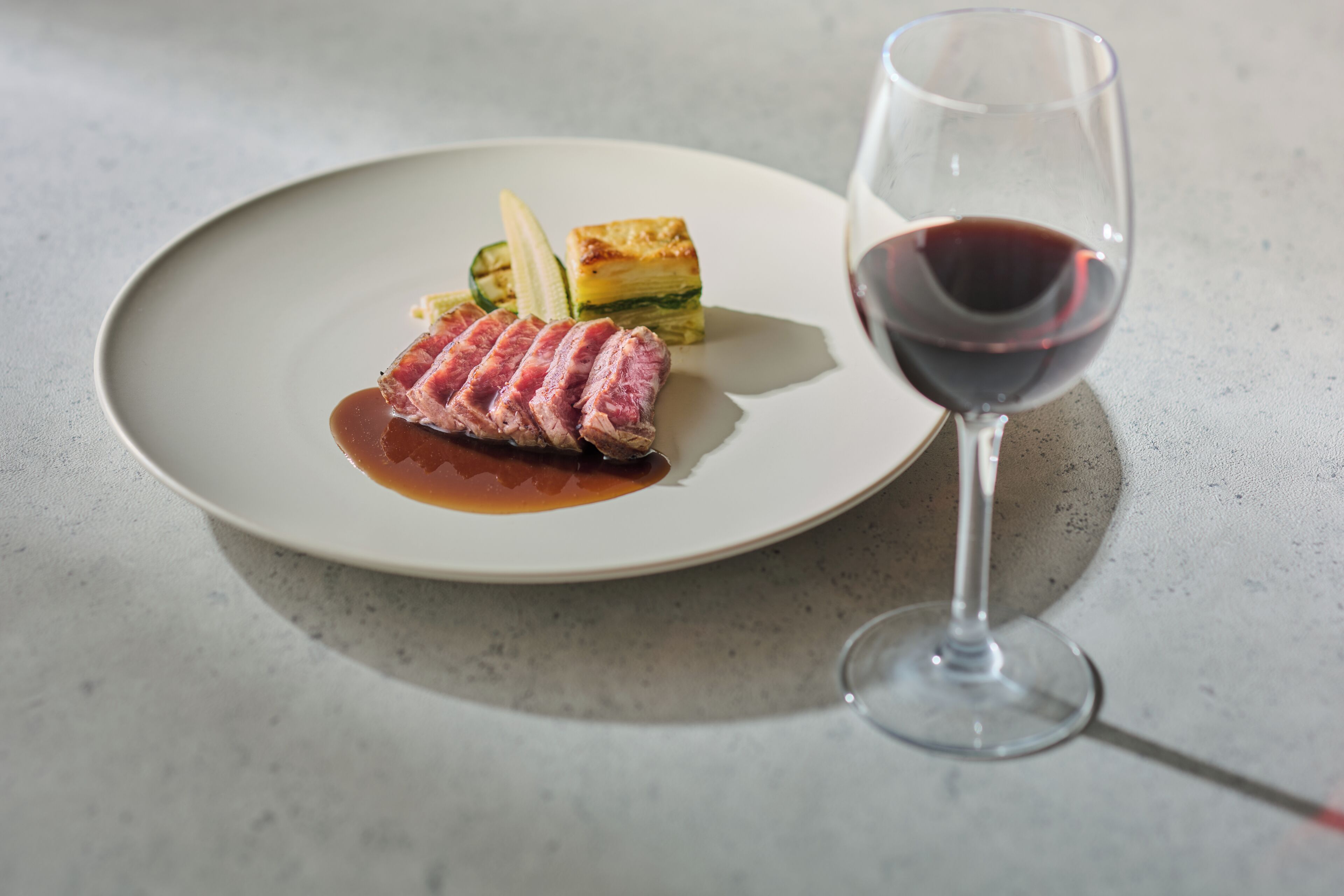 A plate with a steak and vegetables, and a glass of red wine.