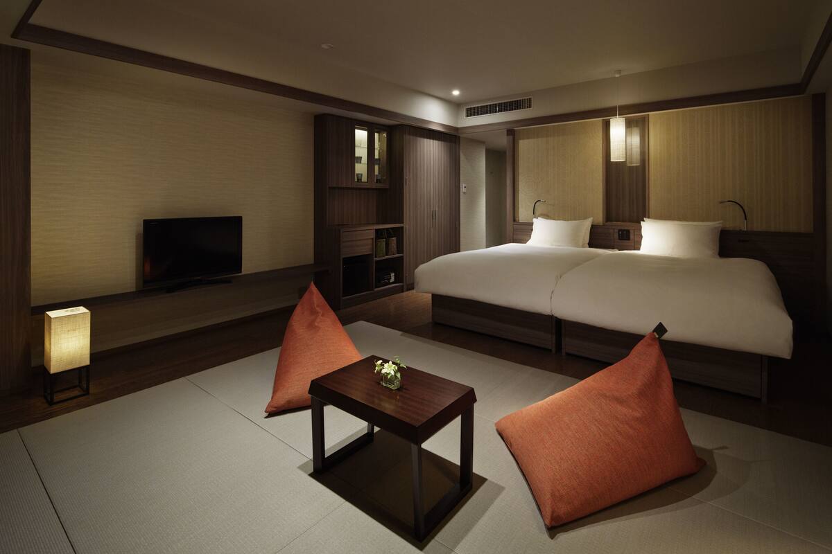 A hotel room with a large bed, a television, a small table, and two pillows.