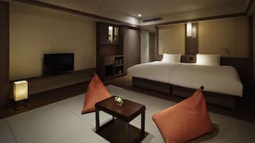 Una habitación de hotel con una cama grande, un televisor, una mesita y dos almohadas.