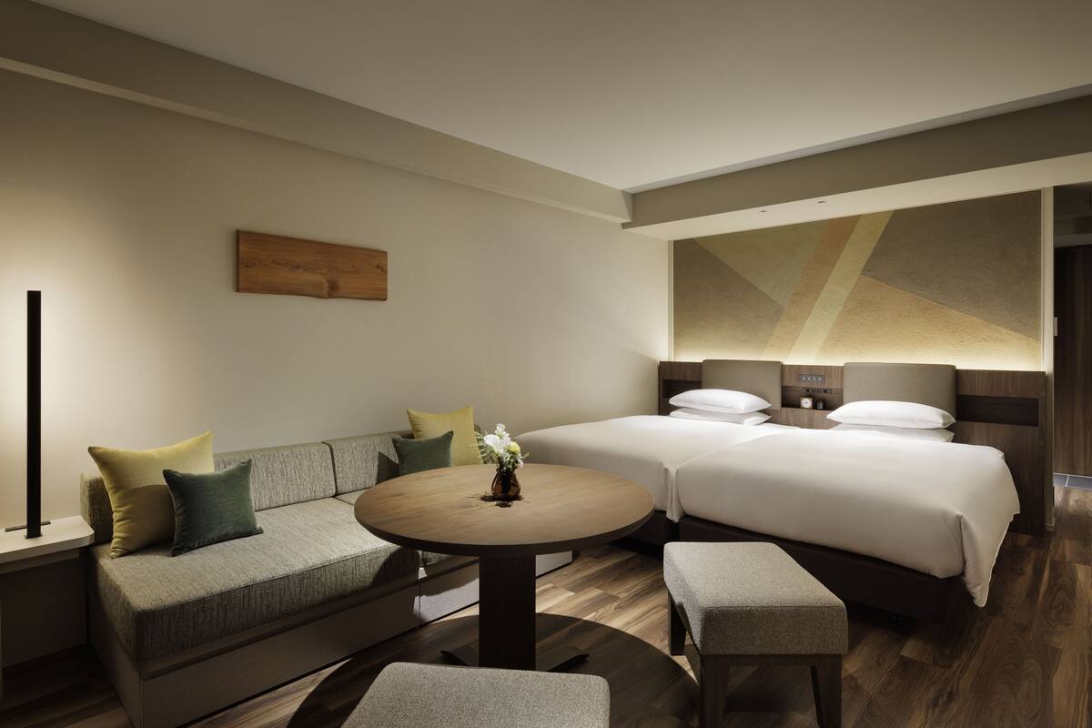 A hotel room with a sofa, a round table, and two beds.