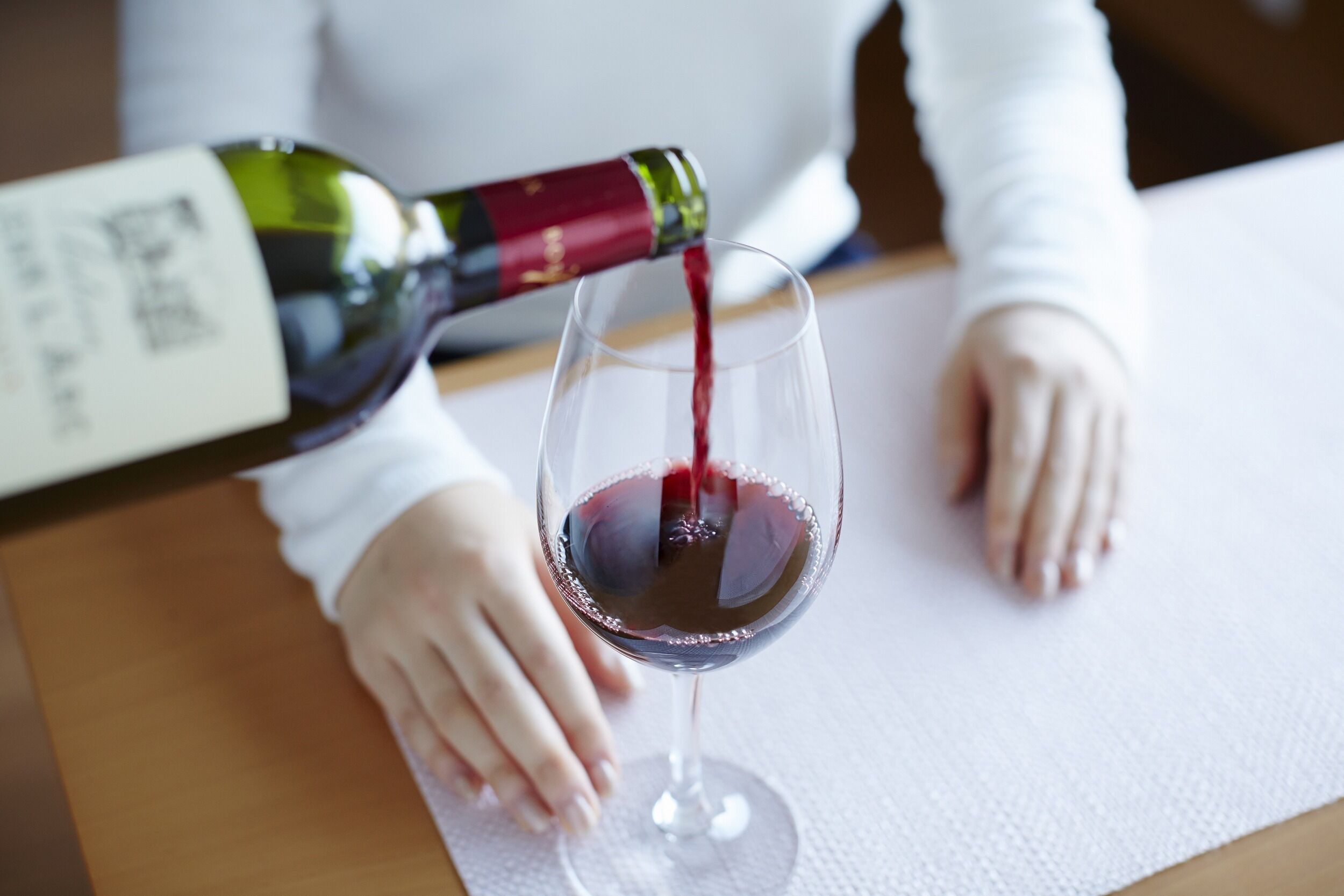 A person pouring red wine into a glass.