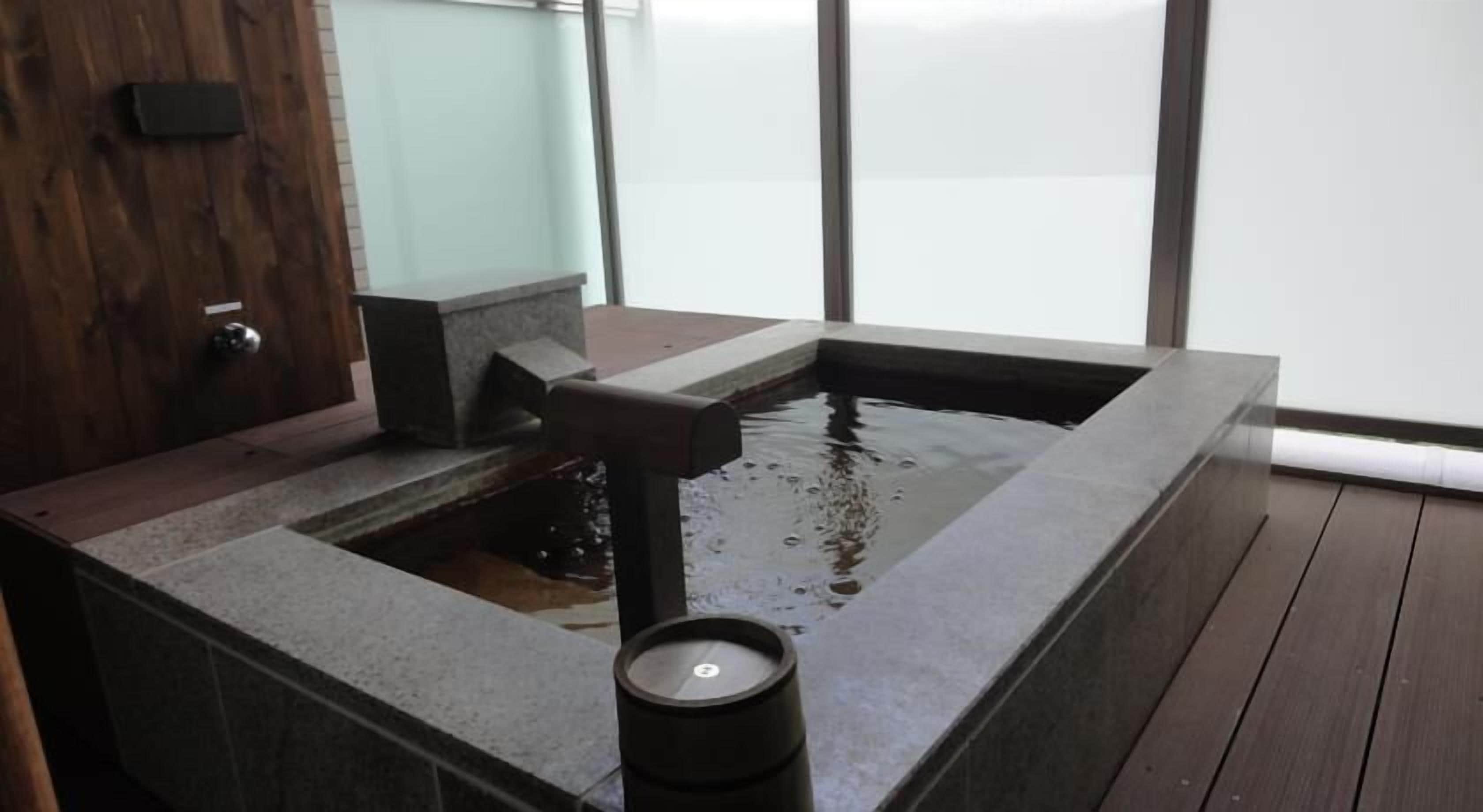 Un baño moderno con un lavabo de piedra y una pequeña fuente de agua.