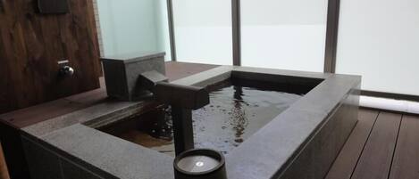 A modern bathroom with a stone sink and a small water feature.