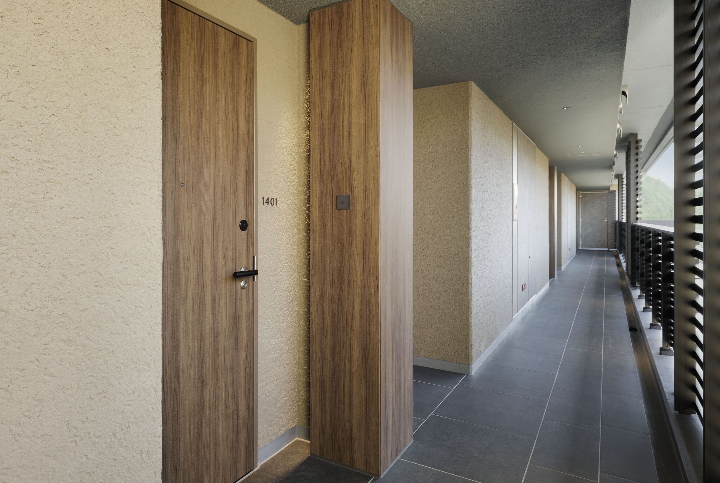 A corridor with wooden doors, numbered 1401, leading to rooms.