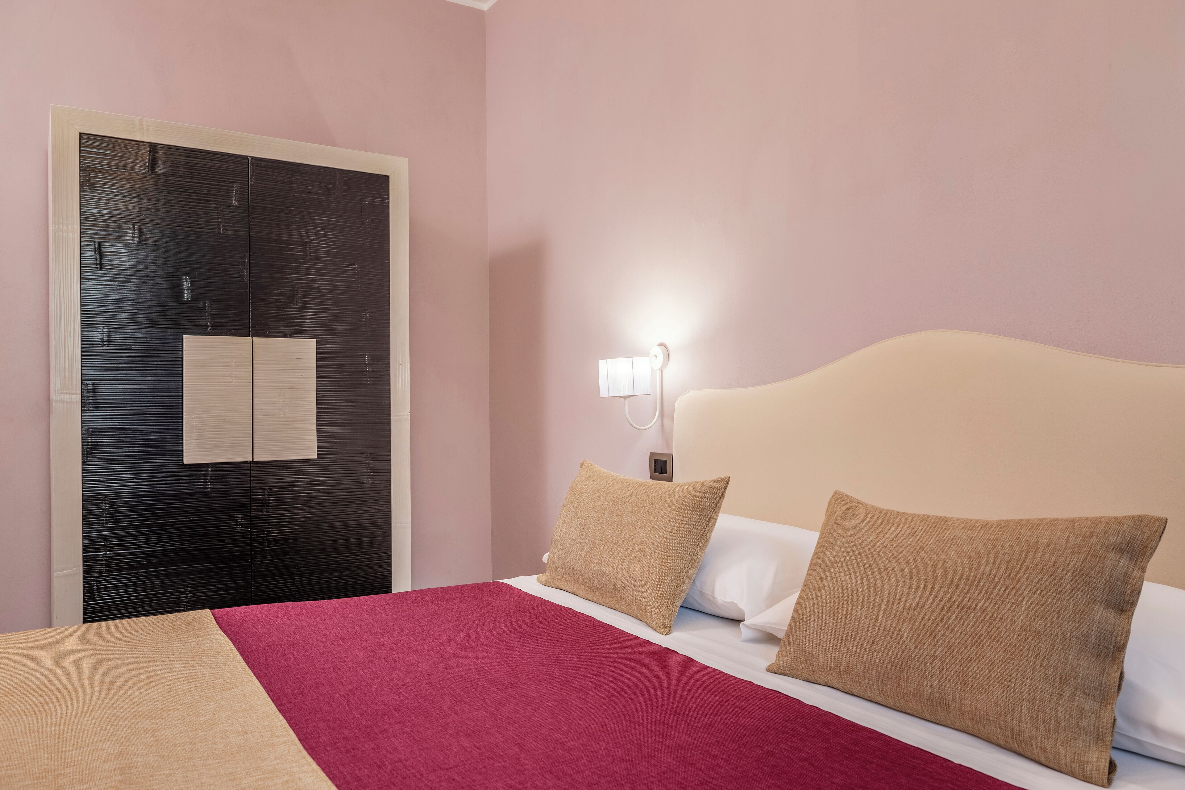 A hotel room with a bed, a wardrobe, and a nightstand.