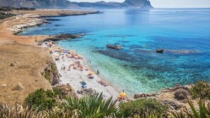 A coastal beach with clear blue waters, rocky outcrops, and a mountainous backdrop. - B&B L'Angolino della Nonna (San Vito Lo Capo)