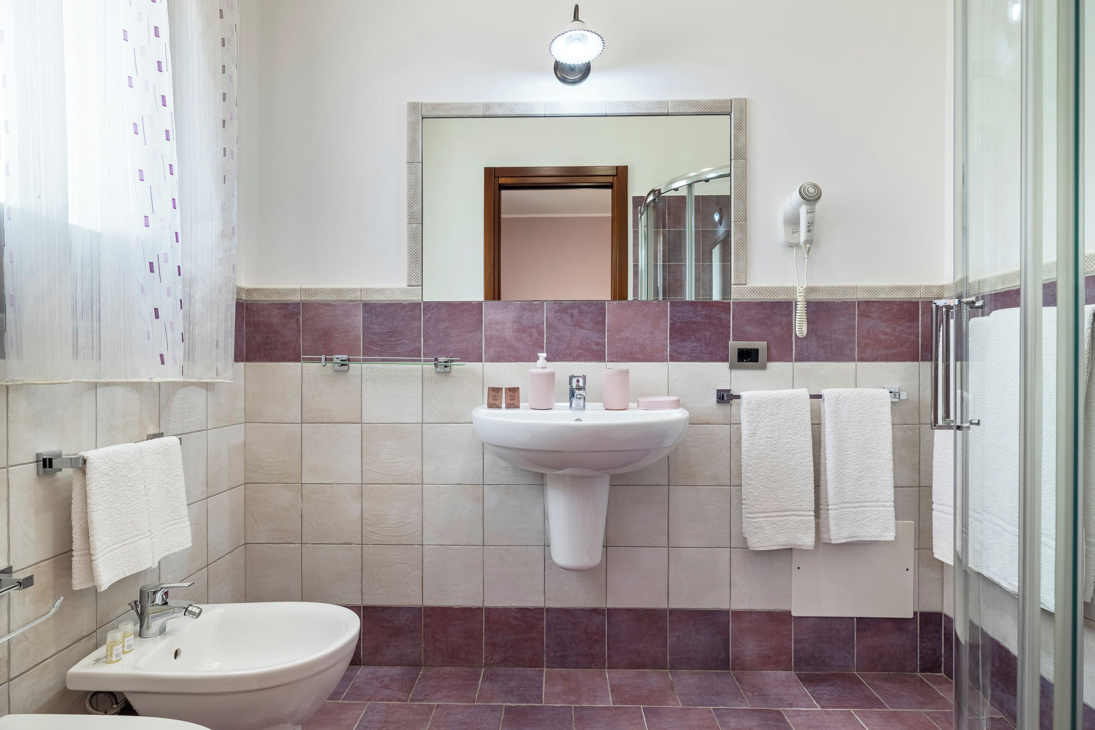 A bathroom with a sink, a bidet, a mirror, and a shower area.