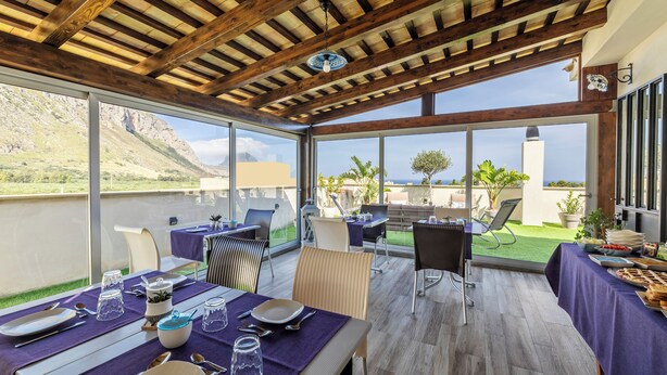 An outdoor dining area with tables set for a meal, overlooking a mountainous landscape. - B&B L'Angolino della Nonna (San Vito Lo Capo)