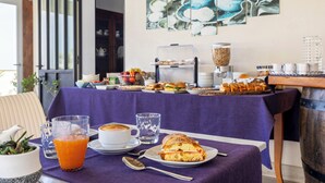 A breakfast buffet with various food items, a coffee cup, and a glass of orange juice on a table with a purple tablecloth. - B&B L'Angolino della Nonna (San Vito Lo Capo)