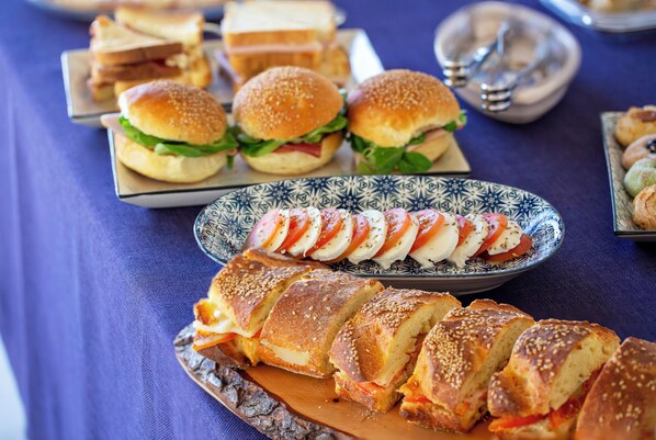 A variety of sandwiches and pastries on a table with a blue tablecloth.