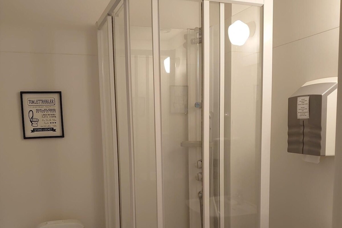 A bathroom with a glass-enclosed shower, a toilet, and a sink.