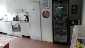 A kitchen with white appliances, a coffee machine, a microwave, and a refrigerator. - Luleå Bed & Breakfast (Luleå)