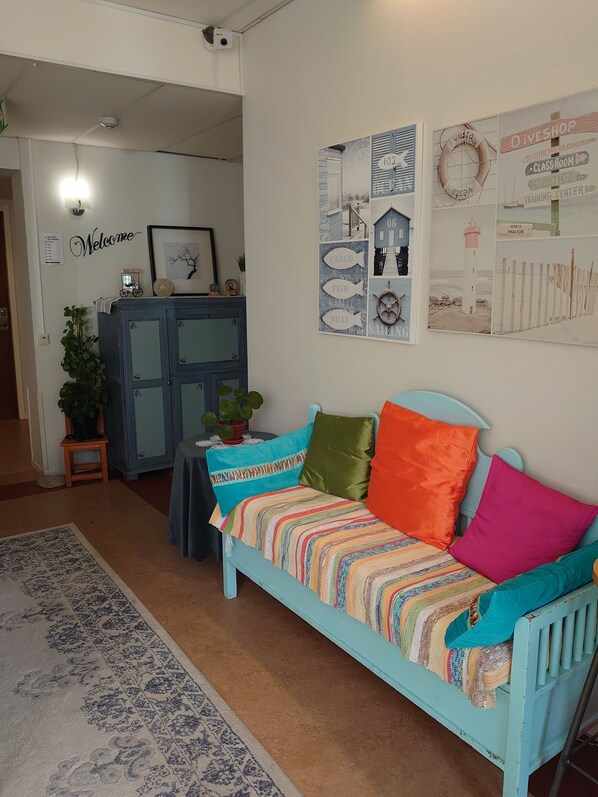 Un salon chaleureux avec un canapé bleu clair agrémenté de coussins colorés, un tapis à motifs et des œuvres d’art murales représentant des thèmes maritimes.