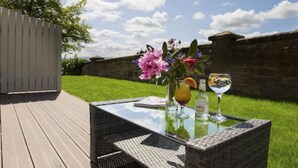 An outdoor patio with a glass table, wicker chairs, and a flower arrangement.