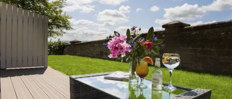 An outdoor patio with a glass table, wicker chairs, and a flower arrangement.
